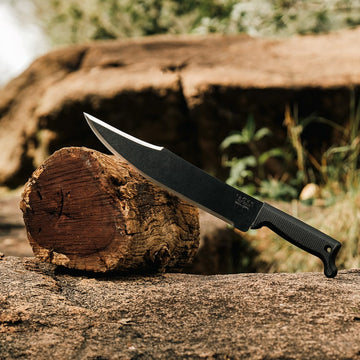 Outdoor lifestyle image of Okapi Bowie machete with Tactical Black handle on forest floor