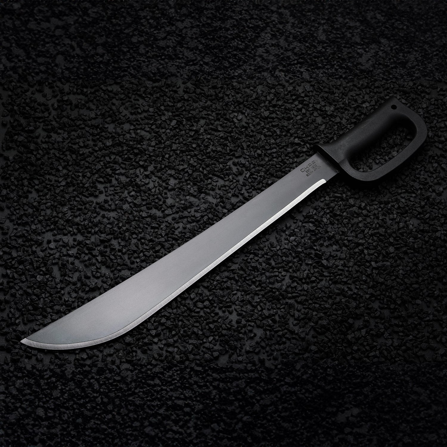 Heavy-duty Okapi D-Ring machete with protective Tactical Black grip displayed in nature
