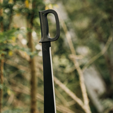 Bushcraft-style Okapi machete with D-Ring guard and black handle shown in lifestyle photo