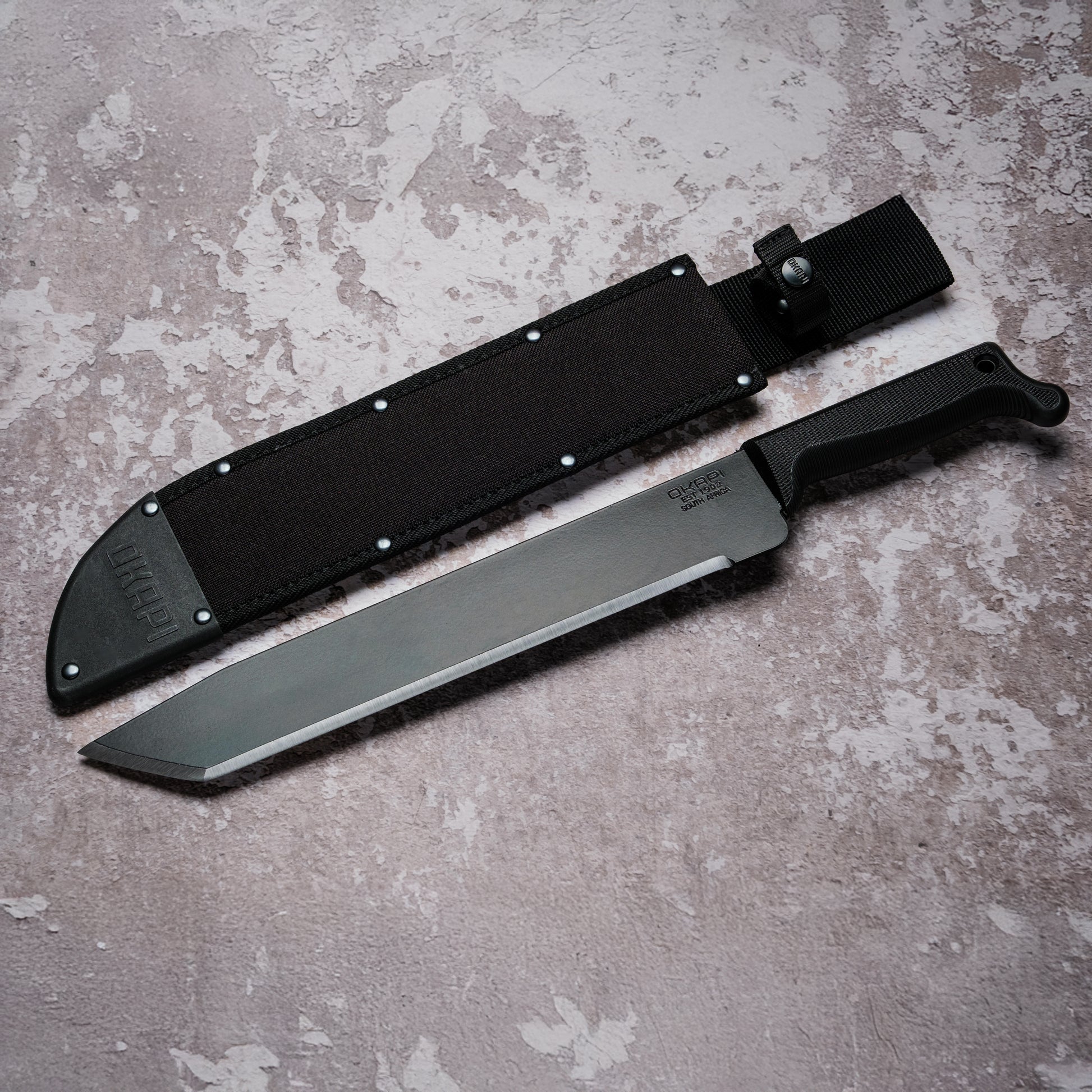 Okapi O-Tanto Machete with black handle with black Sheath on grey background