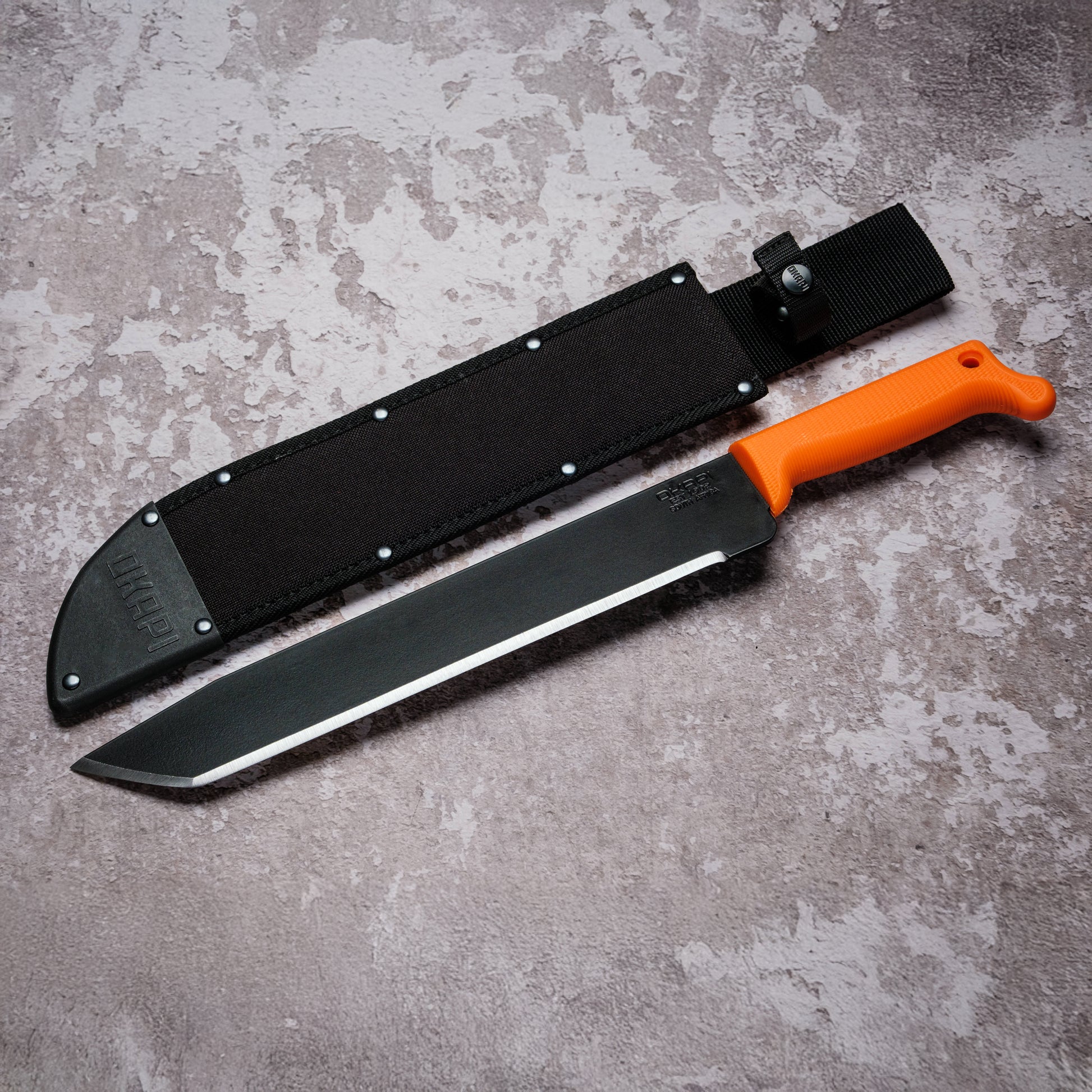 Okapi O-Tanto Machete with Okapi orange handle with black Sheath on grey background