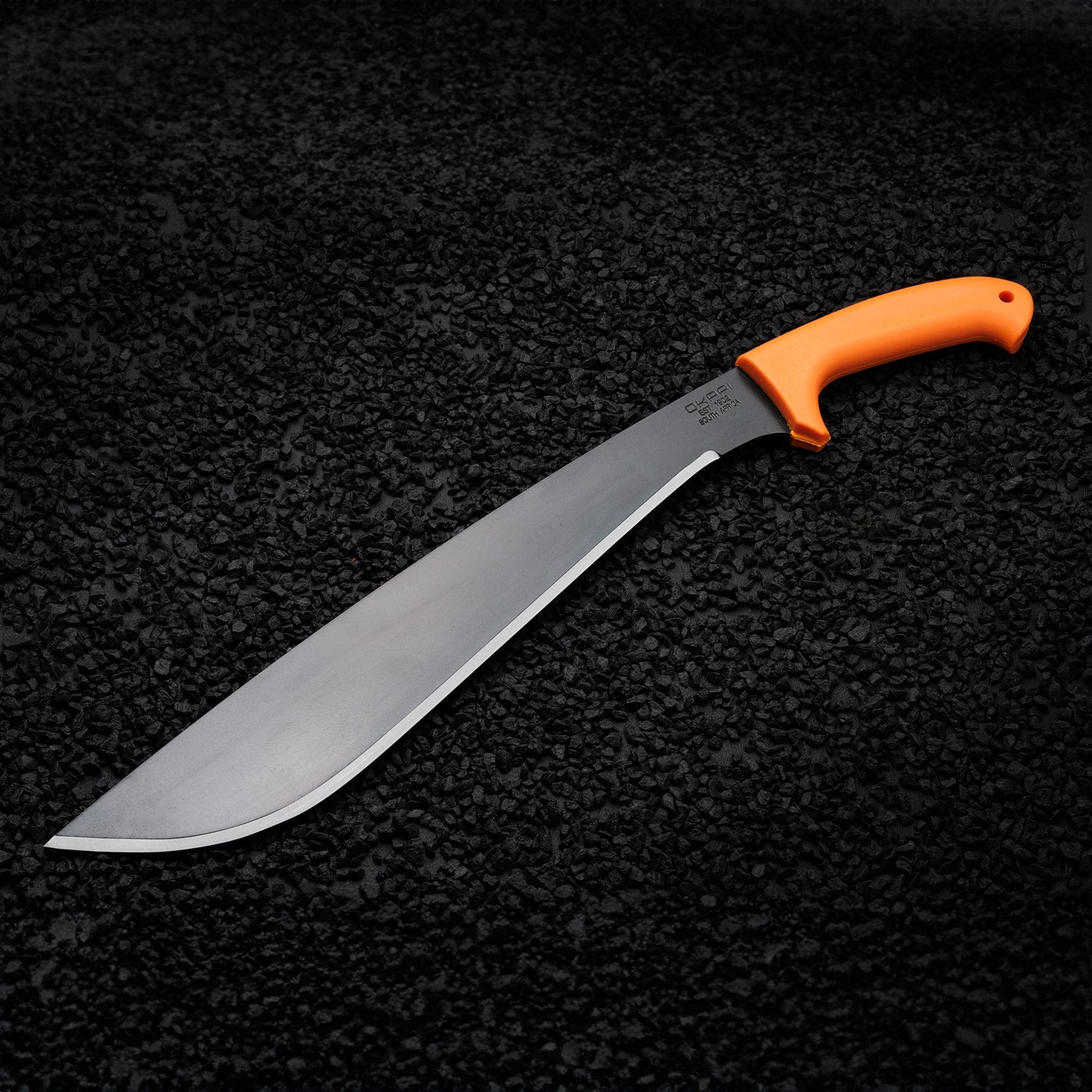 Okapi Jungle machete with Okapi Orange grip positioned on black rock environment