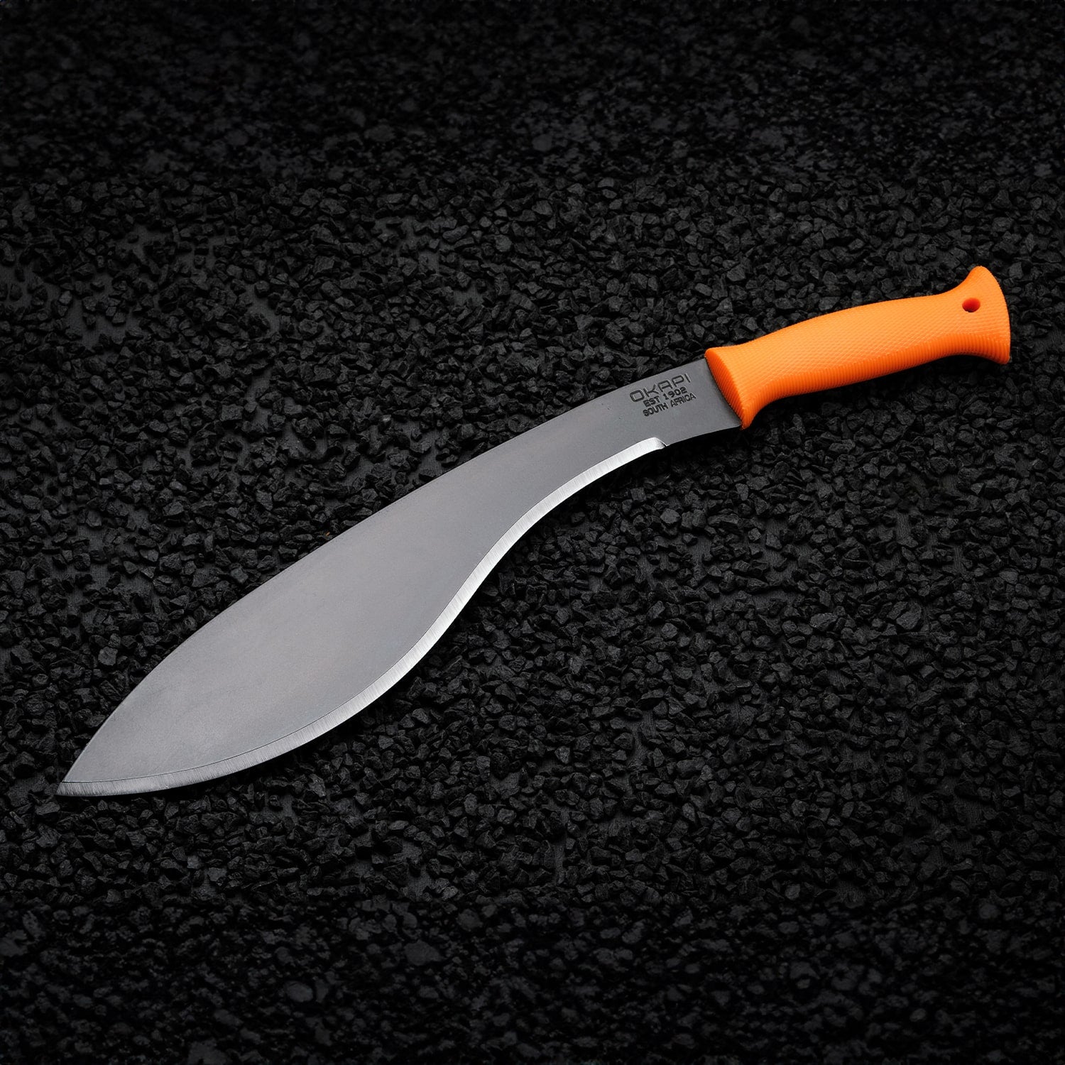 Okapi Orange handled Okapi Kukri-style machete resting on black rock floor