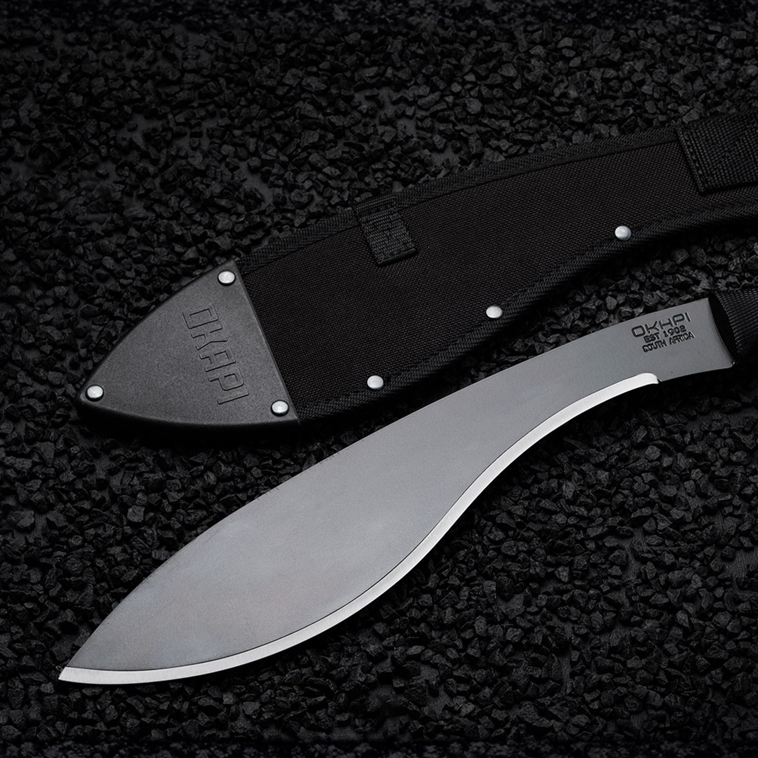 Okapi Kukri Machete Sheath in black on a black stone flooring