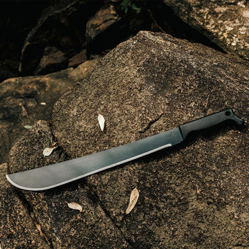 Outdoor gear shot of Okapi Latin machete with black handle on rock surface floor