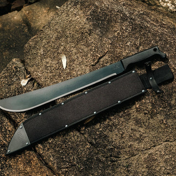 Okapi machete with black tactical grip and sheath laid out in lifestyle environment