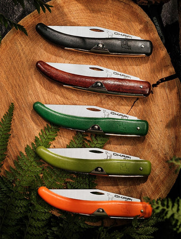 Okapi folding knife with different coloured handles on a wooden background
