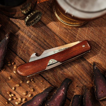 Folded Okapi Biltong & Beer Knife with wooden handle on wooden background