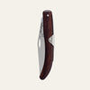 Closed Okapi folding utility knife with ergonomic wooden grip on plain white surface